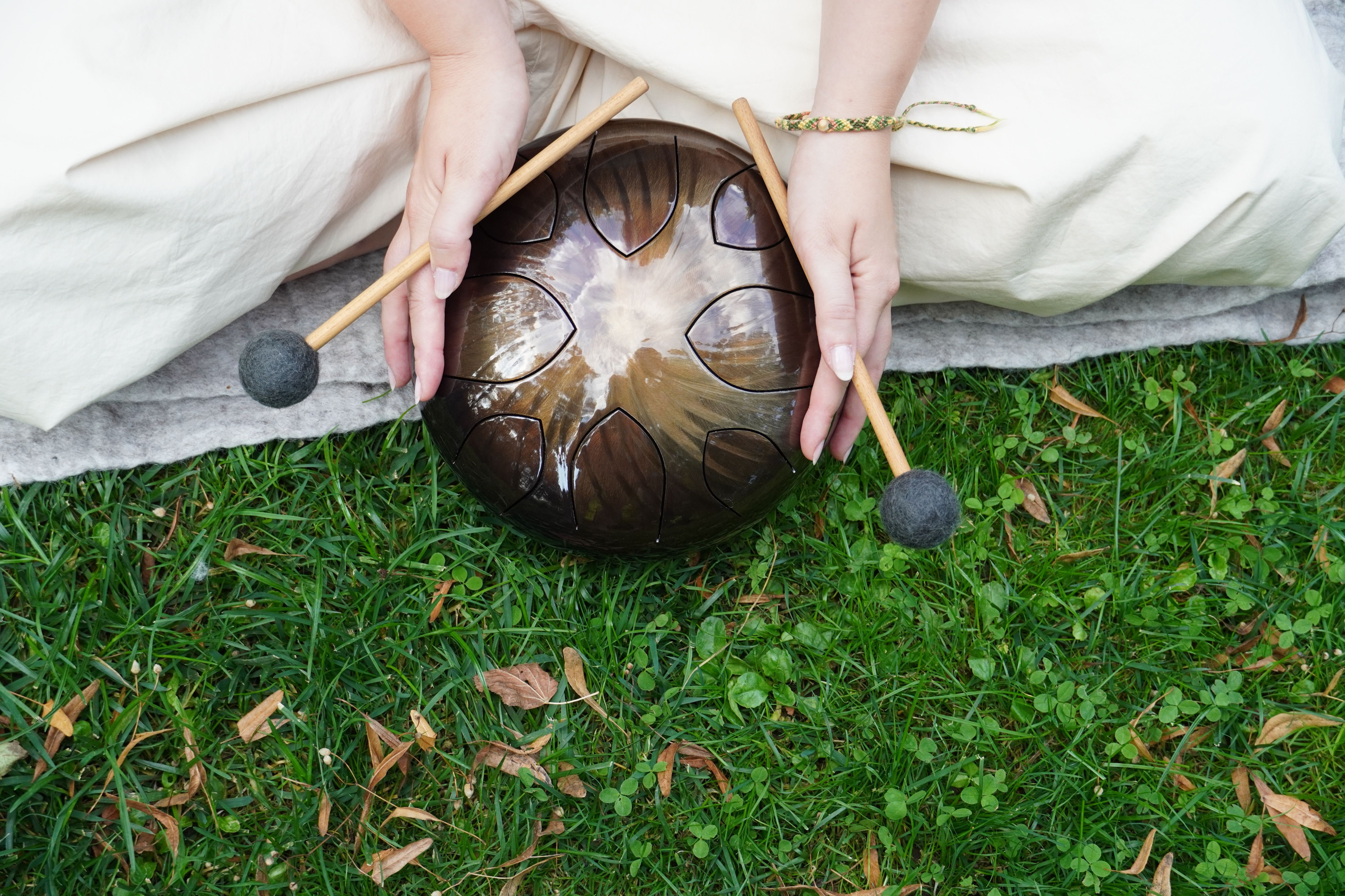 A boy sitting indoors playing a steel tongue drum, expressing creativity and joy.