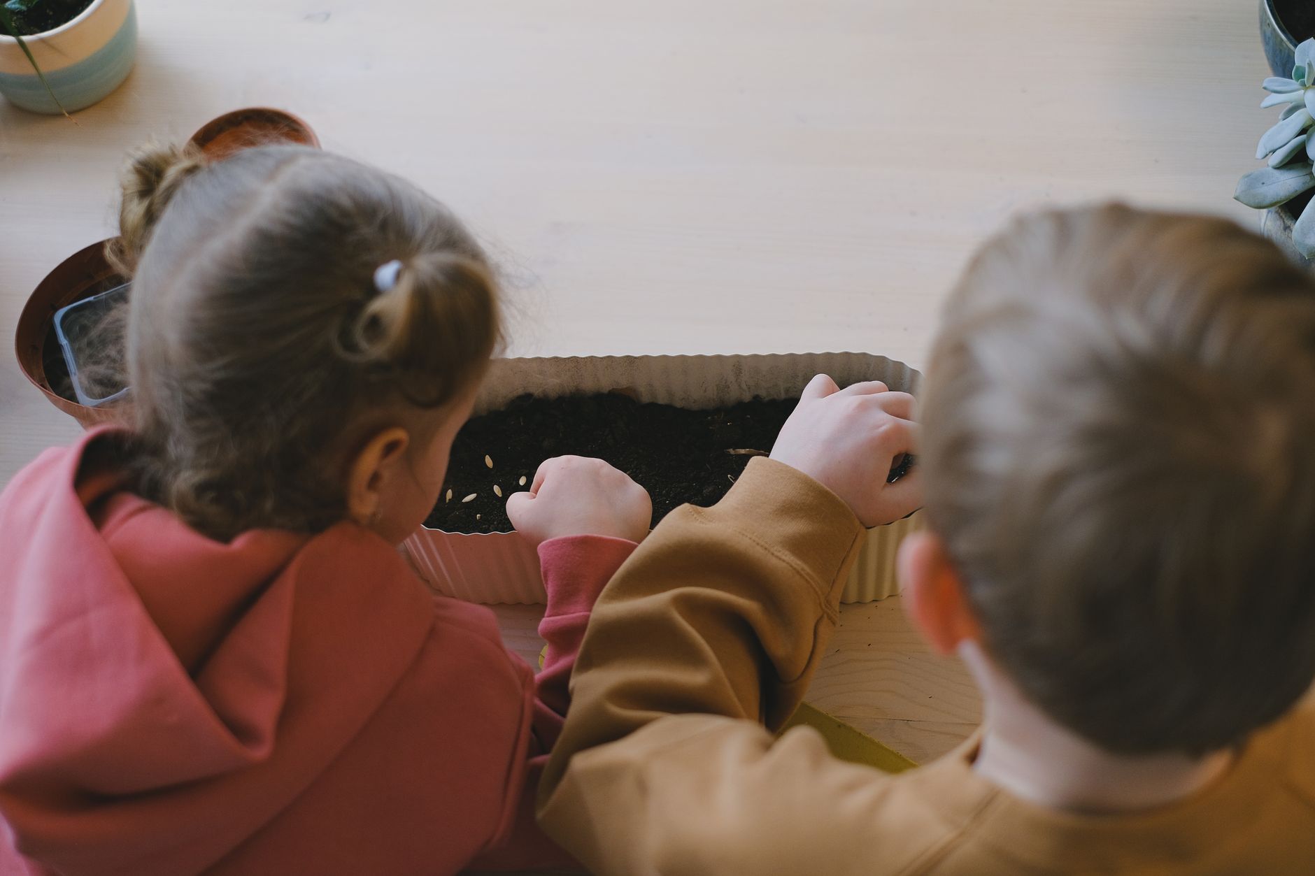 Children planting seeds in a garden container, exploring gardening activities for kids outdoors