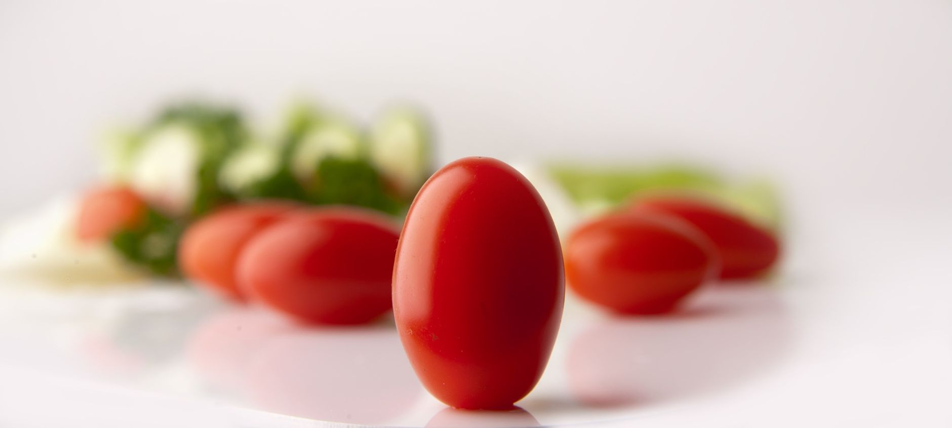 Close-up view of grape tomatoes with assorted vegetables in the background.