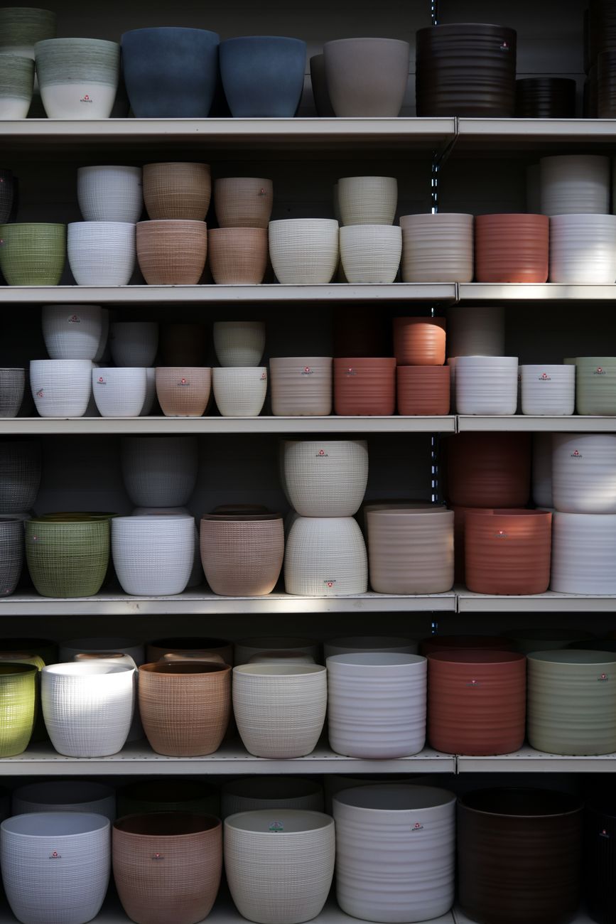A well-organized display of various ceramic plant pots in different colors and sizes.