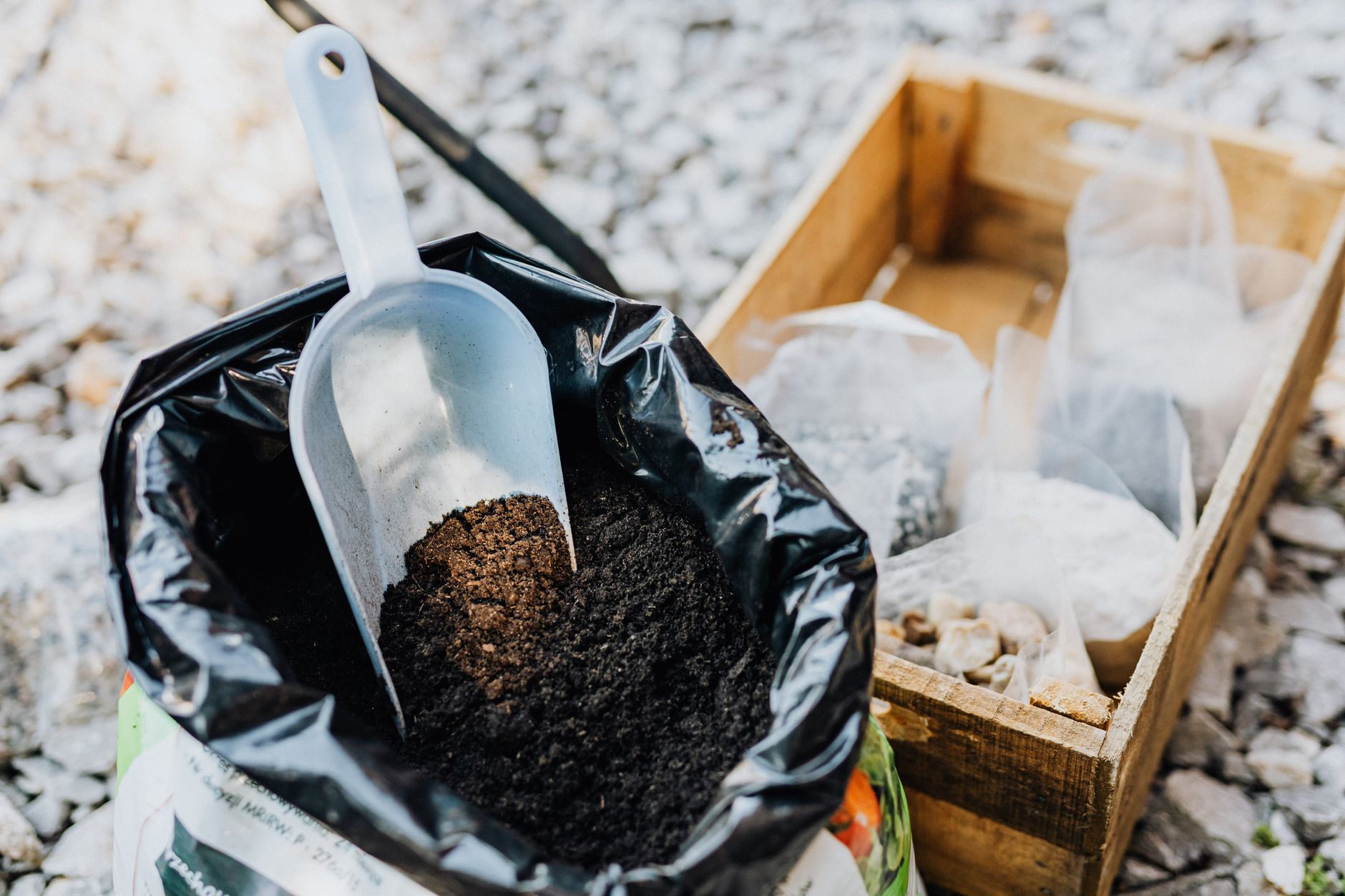 Hands refreshing used potting soil in a container garden, checking texture and moisture before reusing the mix for new plants