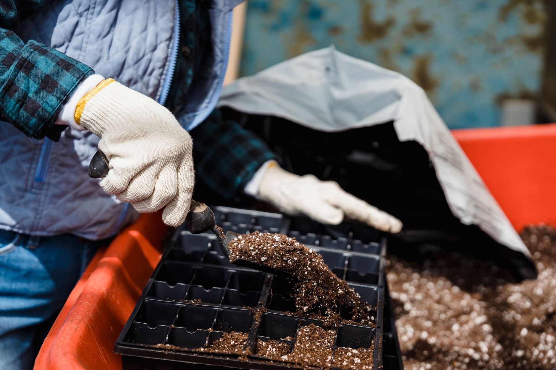 Hands refreshing used potting soil in a container garden, checking texture and moisture before reusing the mix for new plants